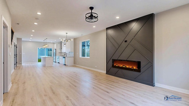 300 N Lockwood Ave, Chicago, IL 60644 - unfurnished living room featuring a chandelier, a fireplace, light wood finished floors, and recessed lighting