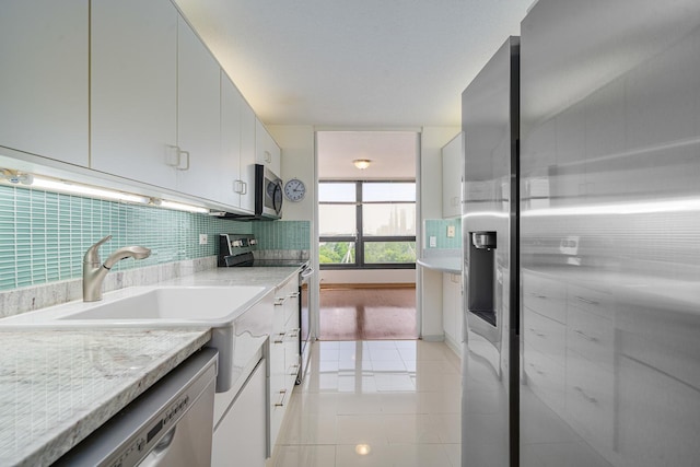 360 E Randolph St Unit 503, Chicago, IL 60601 - kitchen with stainless steel appliances, decorative backsplash, light tile patterned flooring, white cabinets, and light stone counters
