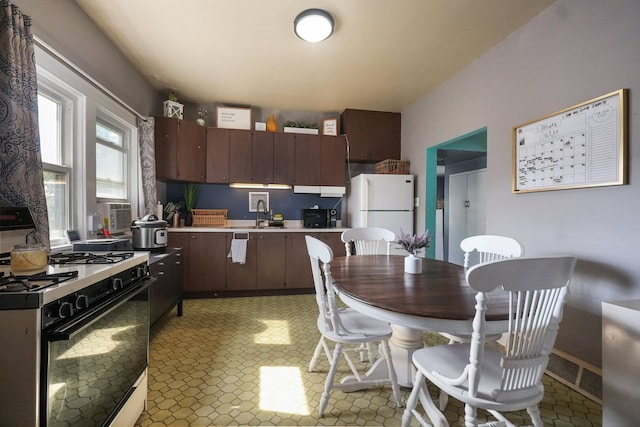208 Frank Ave, Joliet, IL 60435 - kitchen with range with gas cooktop, freestanding refrigerator, light countertops, dark brown cabinets, and light floors