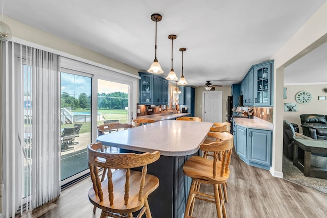 9822 W Pauling Rd, Monee, IL 60449 - kitchen with blue cabinetry, a ceiling fan, light wood-style floors, and a kitchen breakfast bar