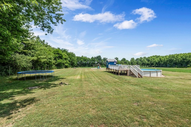 9822 W Pauling Rd, Monee, IL 60449 - view of green lawn with a trampoline, an outdoor pool, a forest view, and a wooden deck