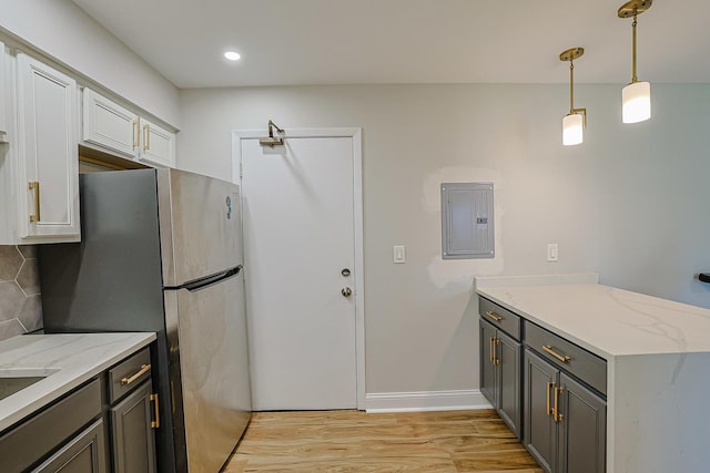 9562 Park Ln Unit 1D, Des Plaines, IL 60016 - kitchen featuring electric panel, freestanding refrigerator, a peninsula, light wood-type flooring, and light stone countertops