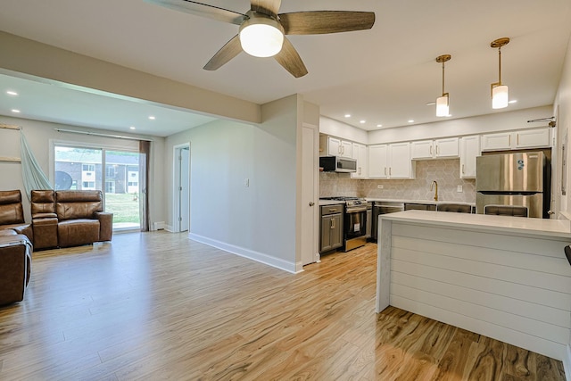 9562 Park Ln Unit 1D, Des Plaines, IL 60016 - kitchen with stainless steel appliances, open floor plan, light wood finished floors, decorative backsplash, and white cabinets