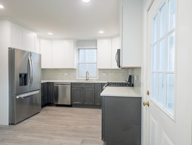 1406 N Artesian Ave, Chicago, IL 60622 - kitchen featuring stainless steel appliances, decorative backsplash, light countertops, white cabinets, and light wood finished floors