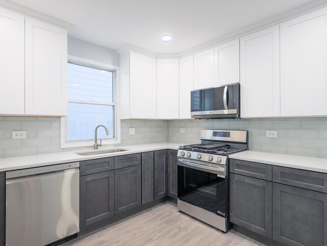 1406 N Artesian Ave, Chicago, IL 60622 - kitchen featuring appliances with stainless steel finishes, light wood-style flooring, light countertops, tasteful backsplash, and white cabinetry