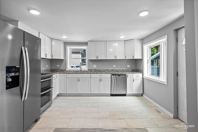 829 Liberty St, Aurora, IL 60505 - kitchen featuring stainless steel appliances, stone countertops, and white cabinetry