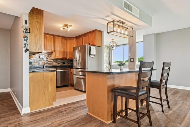 101 Bar Harbour Rd Unit 5N, Schaumburg, IL 60193 - kitchen with appliances with stainless steel finishes, backsplash, a kitchen breakfast bar, light wood-style flooring, and a chandelier