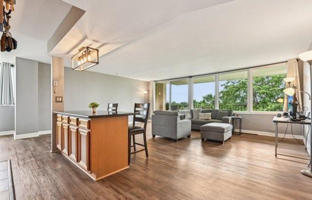 101 Bar Harbour Rd Unit 5N, Schaumburg, IL 60193 - kitchen with brown cabinetry, dark wood-style flooring, a breakfast bar, dark countertops, and open floor plan