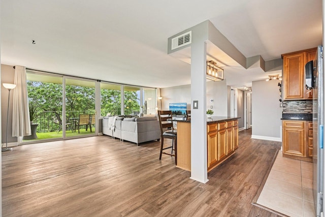 101 Bar Harbour Rd Unit 5N, Schaumburg, IL 60193 - kitchen featuring open floor plan, dark countertops, dark wood-type flooring, backsplash, and brown cabinetry