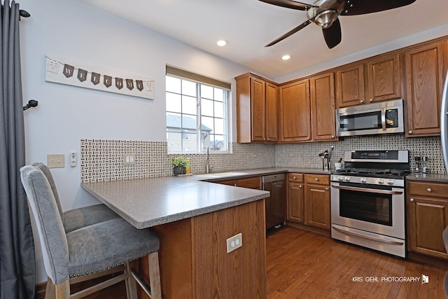 78 Thomas Ct, Grayslake, IL 60030 - kitchen with stainless steel appliances, a peninsula, dark wood-style flooring, ceiling fan, and brown cabinets