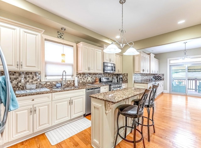3139 Ridgeland Ave, Berwyn, IL 60402 - kitchen featuring stainless steel appliances, dark stone countertops, light wood-style floors, tasteful backsplash, and pendant lighting