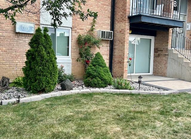 2B Dundee Quarter Unit 101, Palatine, IL 60074 - entrance to property with a balcony, a wall mounted air conditioner, a yard, and brick siding