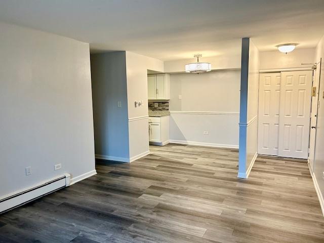 2B Dundee Quarter Unit 101, Palatine, IL 60074 - unfurnished living room featuring a baseboard radiator and wood finished floors