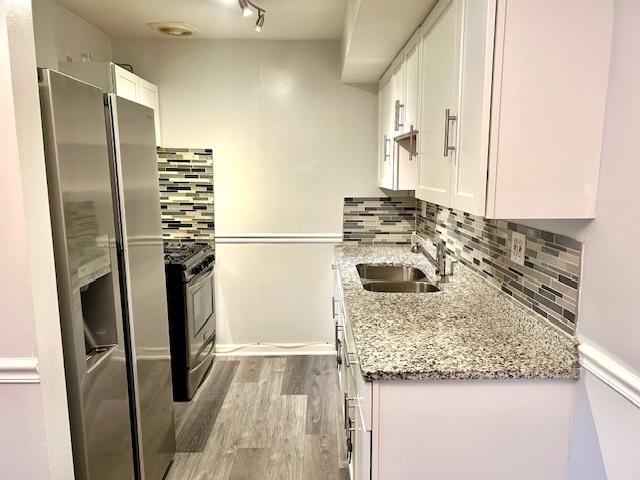 2B Dundee Quarter Unit 101, Palatine, IL 60074 - kitchen with stainless steel appliances, white cabinets, wood finished floors, light stone countertops, and tasteful backsplash