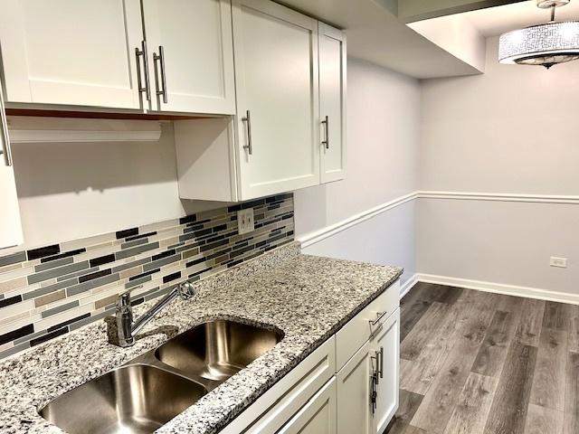 2B Dundee Quarter Unit 101, Palatine, IL 60074 - kitchen with white cabinets, tasteful backsplash, dark wood finished floors, and light stone counters