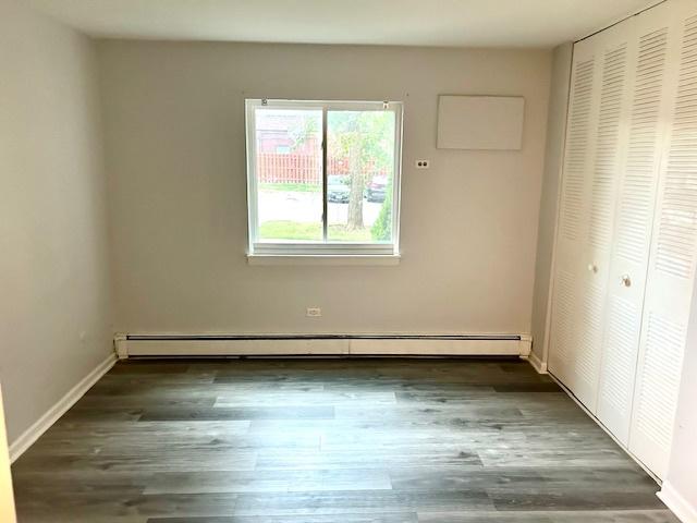 2B Dundee Quarter Unit 101, Palatine, IL 60074 - unfurnished bedroom featuring a baseboard radiator, a closet, and wood finished floors
