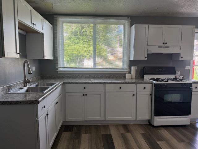 622 N Pine St, Waukegan, IL 60085 - kitchen with range with gas stovetop, under cabinet range hood, a textured ceiling, and white cabinets