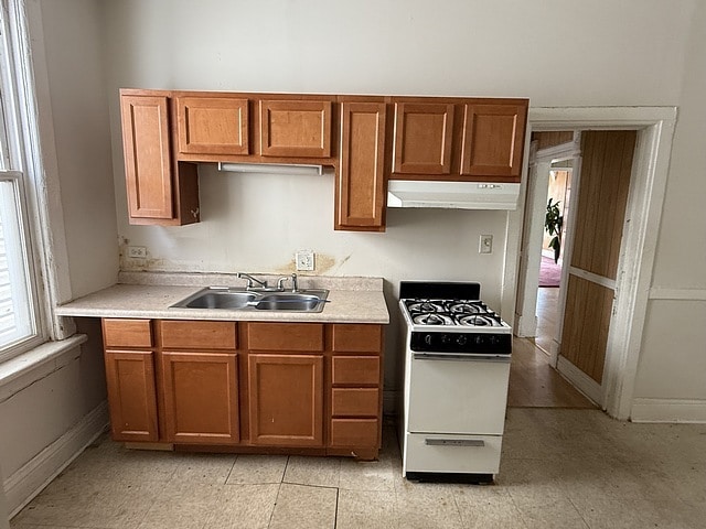 6044 S Justine St, Chicago, IL 60636 - kitchen with white gas range oven, under cabinet range hood, light countertops, and brown cabinets