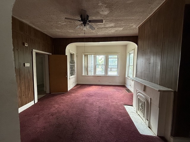 6044 S Justine St, Chicago, IL 60636 - empty room with wood walls, ceiling fan, arched walkways, carpet, and a fireplace with flush hearth