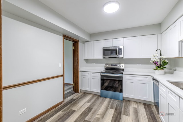 851 Sutton Ct, Lincolnshire, IL 60069 - kitchen featuring appliances with stainless steel finishes, light wood-style floors, white cabinetry, and light countertops