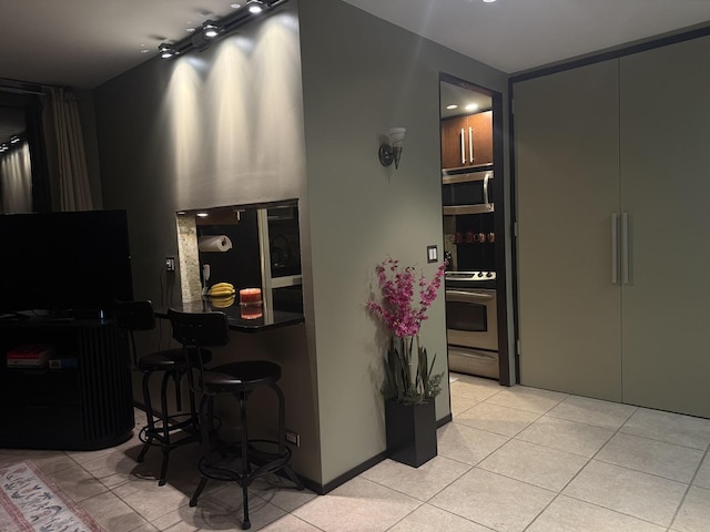 1300 N Astor St Unit 6B, Chicago, IL 60610 - kitchen featuring stainless steel appliances, light tile patterned floors, and a kitchen bar
