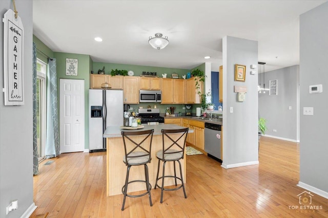 2039 Muirfield Dr, Yorkville, IL 60560 - kitchen with stainless steel appliances, light wood-style floors, light brown cabinetry, a kitchen island, and a breakfast bar
