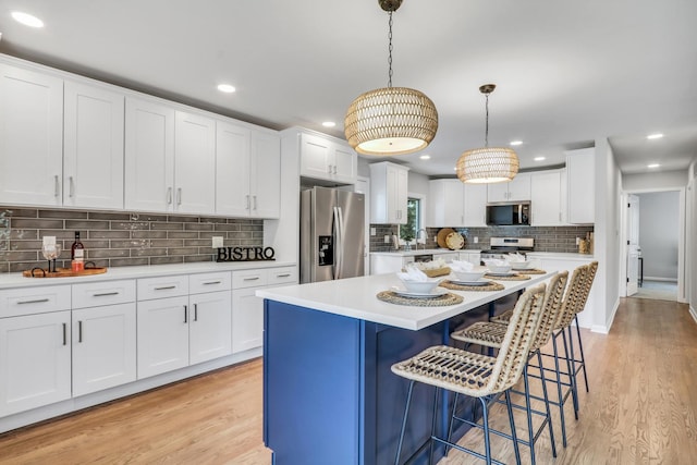 31340 N Liberty Rd, Grayslake, IL 60030 - kitchen featuring appliances with stainless steel finishes, backsplash, light countertops, a breakfast bar, and white cabinets