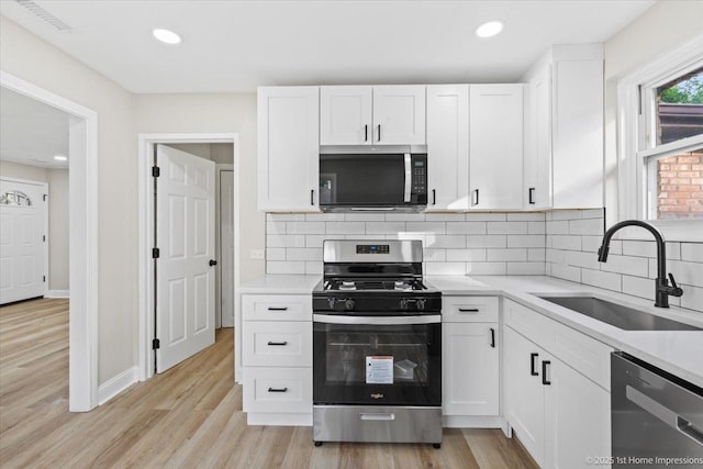 214 Marquette St, Park Forest, IL 60466 - kitchen featuring appliances with stainless steel finishes, white cabinetry, light countertops, light wood-style floors, and backsplash
