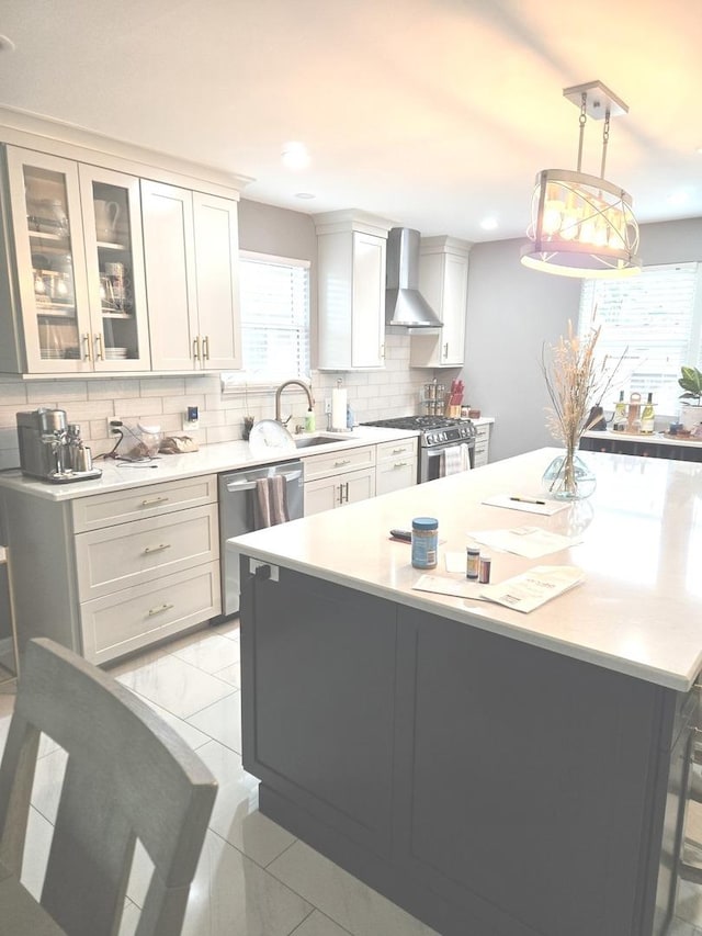 452 S Walnut St, Bensenville, IL 60106 - kitchen featuring wall chimney range hood, appliances with stainless steel finishes, light countertops, decorative backsplash, and a kitchen island