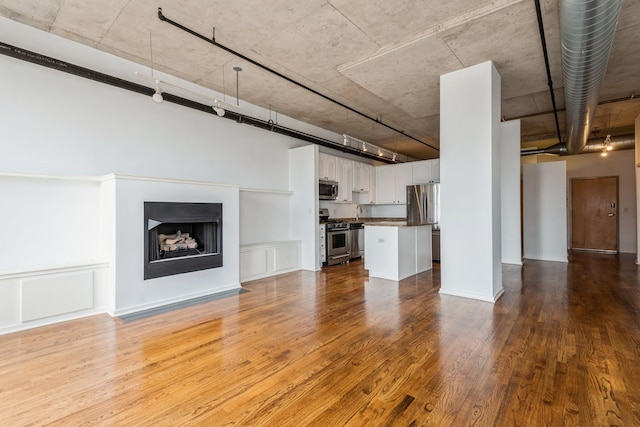 6 S Laflin St Unit 712, Chicago, IL 60607 - unfurnished living room featuring wood finished floors, a fireplace, a towering ceiling, and rail lighting