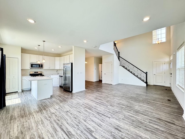 15041 W Quincy Cir, Manhattan, IL 60442 - kitchen featuring stainless steel appliances, open floor plan, light countertops, light wood-type flooring, and white cabinets