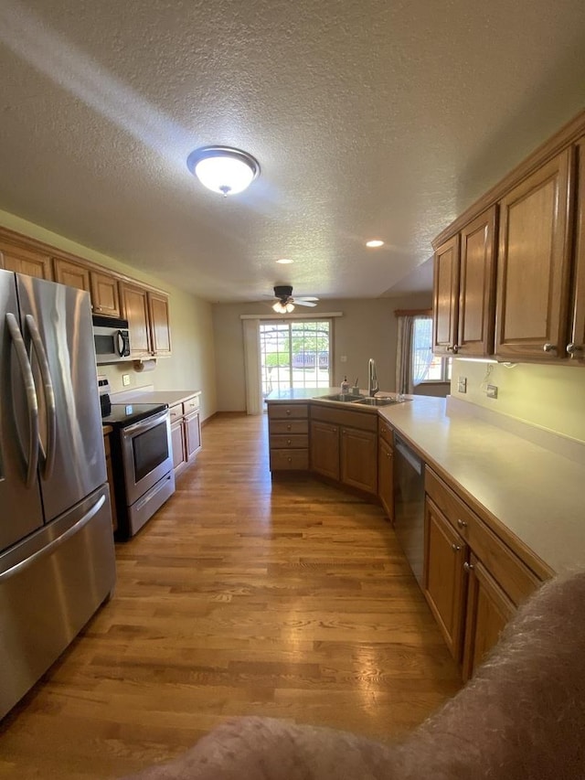 831 Oriole Dr, Peotone, IL 60468 - kitchen featuring stainless steel appliances, light wood finished floors, a textured ceiling, a peninsula, and a ceiling fan