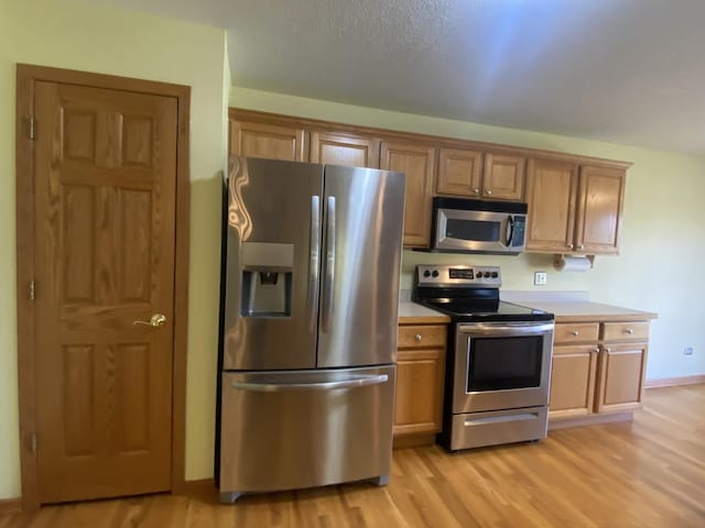 831 Oriole Dr, Peotone, IL 60468 - kitchen featuring stainless steel appliances, light wood-type flooring, light countertops, and brown cabinetry
