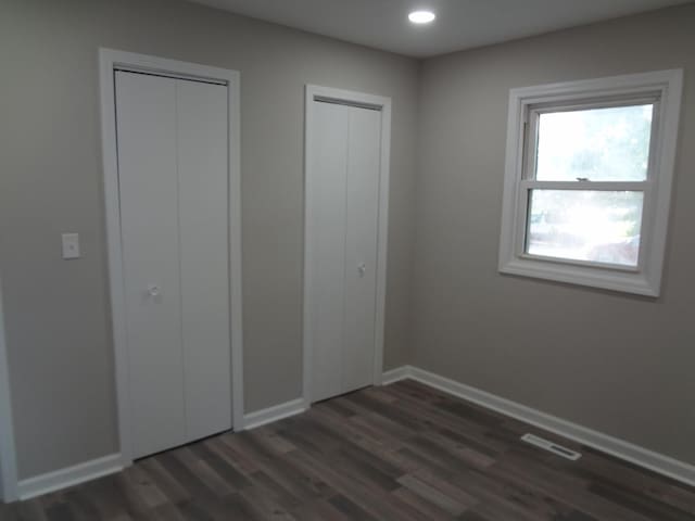 210 Caddy Ave, Carpentersville, IL 60110 - unfurnished bedroom with dark wood finished floors, recessed lighting, and two closets