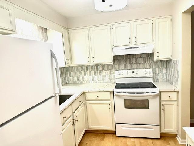 2317 N Neva Ave Unit 106A, Chicago, IL 60707 - kitchen with white appliances, under cabinet range hood, light wood finished floors, tasteful backsplash, and white cabinetry