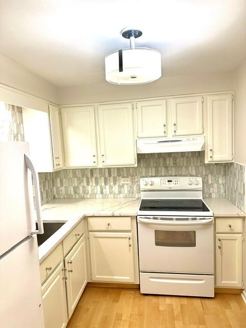 2317 N Neva Ave Unit 106A, Chicago, IL 60707 - kitchen with white appliances, under cabinet range hood, light wood-style flooring, and backsplash