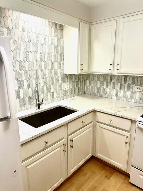 2317 N Neva Ave Unit 106A, Chicago, IL 60707 - kitchen with light wood finished floors, white cabinets, light stone countertops, and backsplash