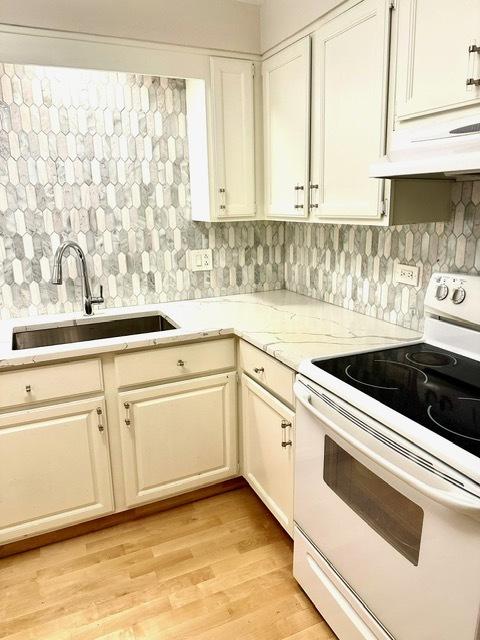 2317 N Neva Ave Unit 106A, Chicago, IL 60707 - kitchen featuring white electric range oven, backsplash, light wood-type flooring, light stone countertops, and white cabinetry