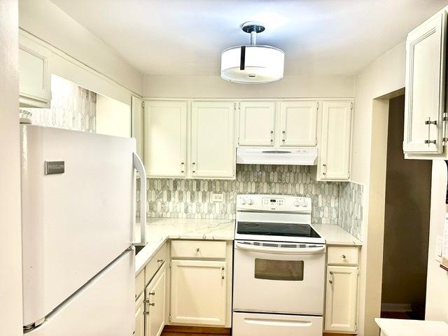 2317 N Neva Ave Unit 106A, Chicago, IL 60707 - kitchen with white appliances, under cabinet range hood, white cabinets, decorative backsplash, and light stone counters