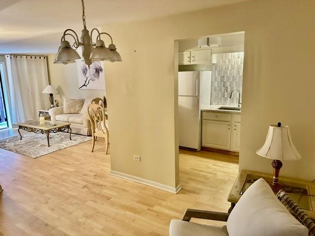 2317 N Neva Ave Unit 106A, Chicago, IL 60707 - living room with light wood finished floors and a chandelier