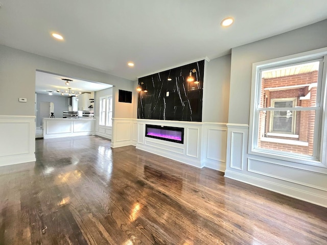8109 S Marquette Ave, Chicago, IL 60617 - unfurnished living room with a decorative wall, a glass covered fireplace, wood finished floors, a wainscoted wall, and recessed lighting