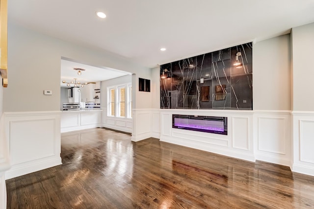 8109 S Marquette Ave, Chicago, IL 60617 - unfurnished living room with a glass covered fireplace, a decorative wall, wood finished floors, recessed lighting, and a wainscoted wall