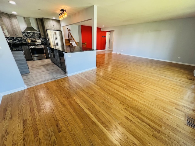 189 Ambleside Rd, Des Plaines, IL 60016 - kitchen featuring appliances with stainless steel finishes, wall chimney range hood, light wood-style floors, dark countertops, and tasteful backsplash