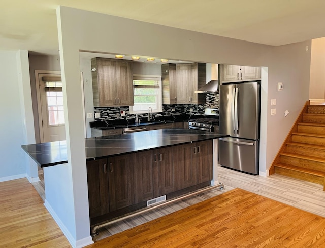 189 Ambleside Rd, Des Plaines, IL 60016 - kitchen with stainless steel appliances, wall chimney range hood, light wood-style floors, dark countertops, and tasteful backsplash
