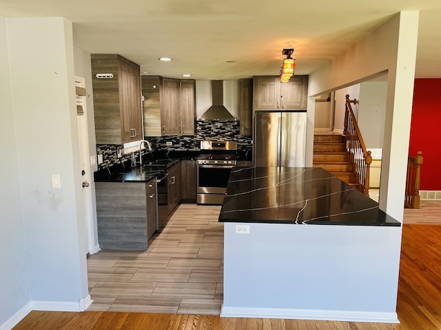 189 Ambleside Rd, Des Plaines, IL 60016 - kitchen featuring wall chimney range hood, appliances with stainless steel finishes, dark countertops, a kitchen island, and backsplash