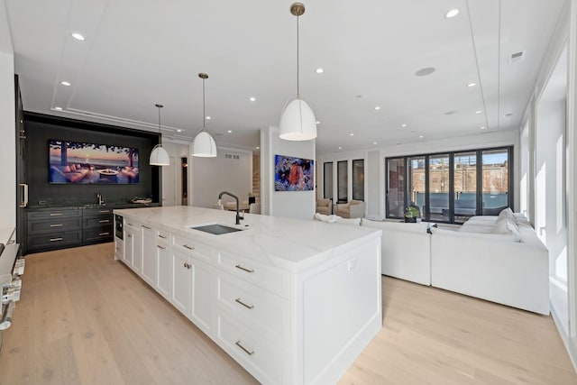 116 N Willard Ct Unit 301, Chicago, IL 60607 - kitchen featuring open floor plan, white cabinets, light wood finished floors, light stone countertops, and a spacious island