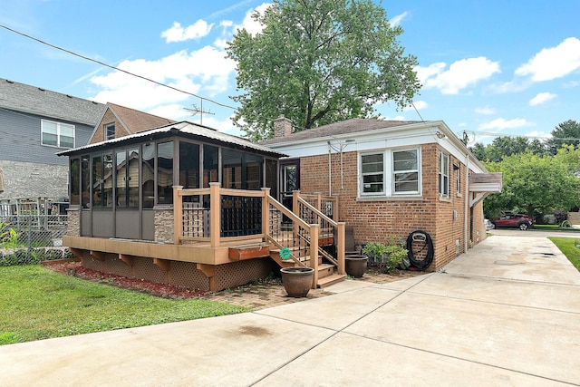 3334 W 114th St, Chicago, IL 60655 - rear view of house with a sunroom, brick siding, concrete driveway, a chimney, and a deck