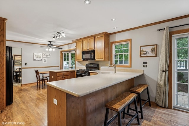 732 Green Castle Ct, West Dundee, IL 60118 - kitchen with black appliances, a peninsula, crown molding, light wood-type flooring, and light countertops