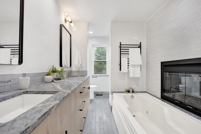 826 S Bell Ave, Chicago, IL 60612 - bathroom featuring a tub with jets, double vanity, a glass covered fireplace, and recessed lighting