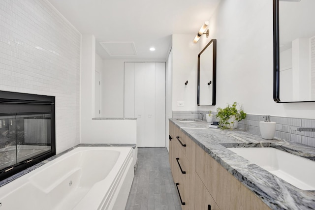 826 S Bell Ave, Chicago, IL 60612 - full bathroom with a whirlpool tub, double vanity, recessed lighting, wood finished floors, and a glass covered fireplace